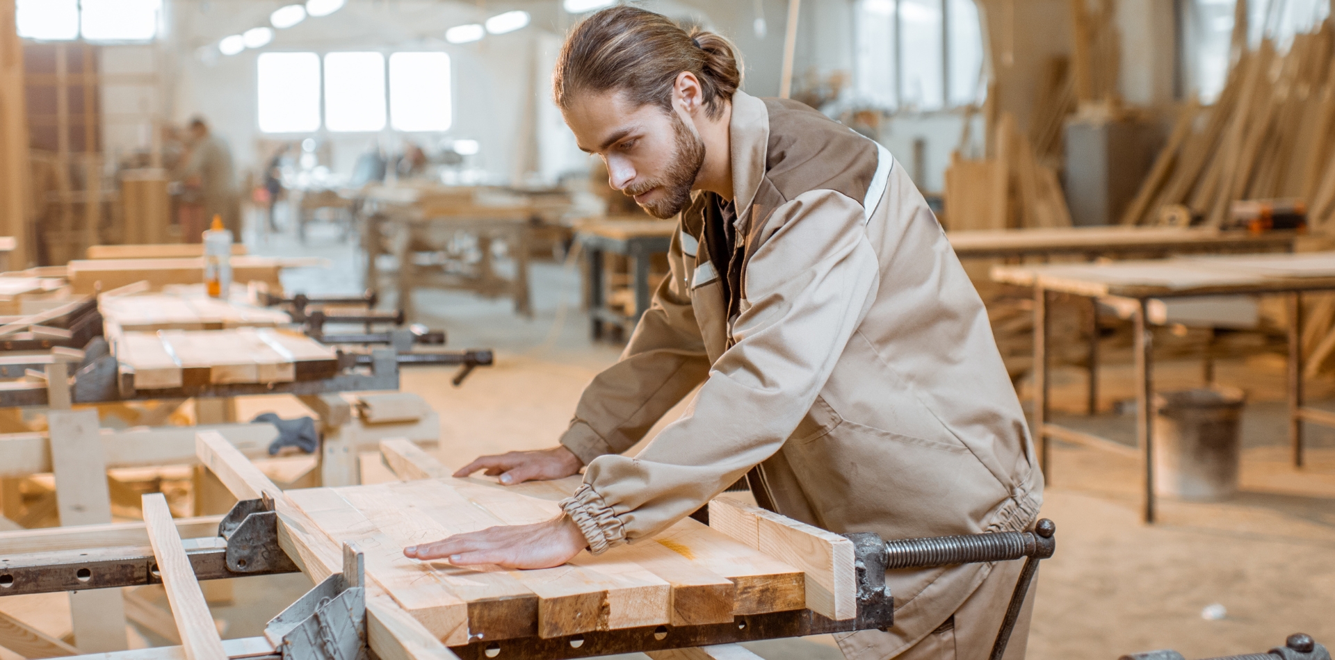 A carpenter working intently on a wooden project in a workshop.